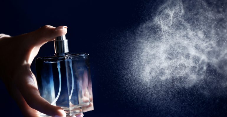 Woman,Spraying,Perfume,On,Dark,Background,,Closeup